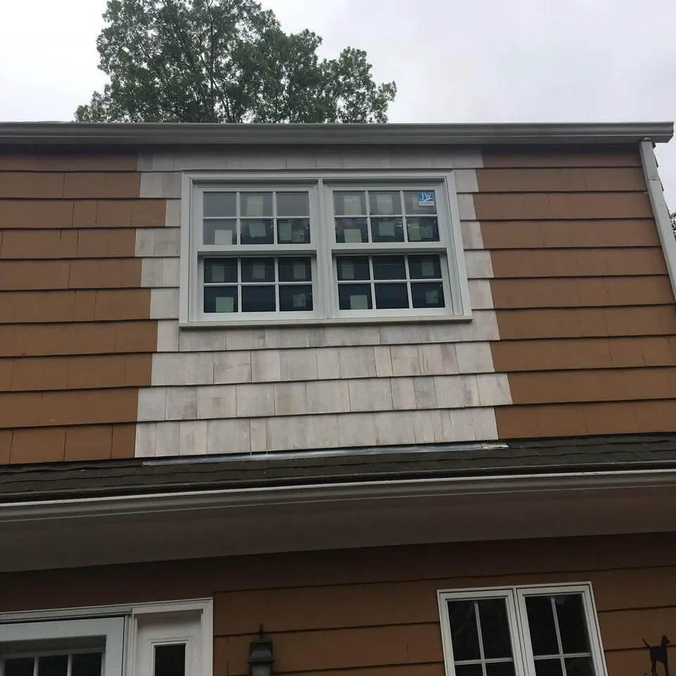 Paired white double-hung replacement windows set into a cedar-shingled dormer